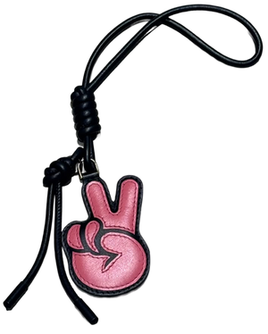 A pink leather keychain charm shaped like a peace sign hand, attached to a black braided cord and tassel on a white background.